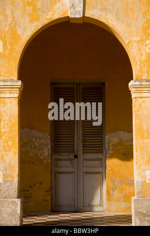 Weathered giallo francese coloniale a archway e sportello in Phnom Penh Cambogia Foto Stock