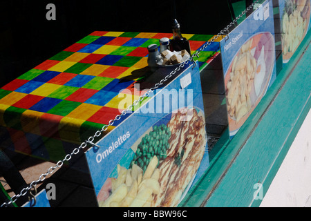 Colorati nella tabella a scacchi il panno e menu in a Seaside Cafe finestra in Weston-super-Mare Foto Stock
