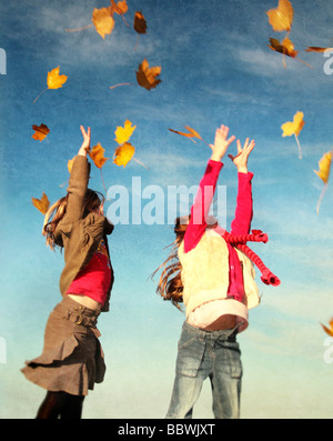 Due ragazze la cattura di foglie che cadono in autunno Foto Stock