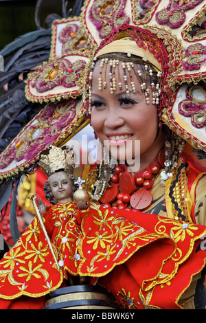 Donna con costume sinulog e un Santo Niño doll Foto Stock