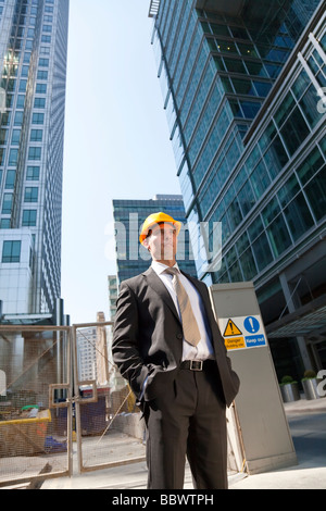 Shot che mostra un uomo vestito con una tuta e casco su una costruzione sito in un moderno ambiente di città Foto Stock