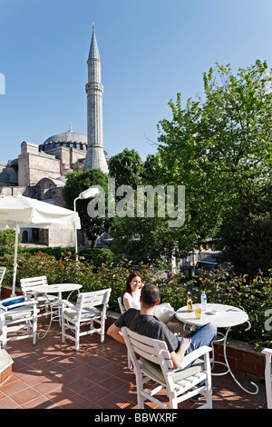 Coppia giovane in appoggio in una caffetteria con terrazza che si affaccia la Basilica di Santa Sofia, Sultanahmet, Istanbul, Turchia Foto Stock