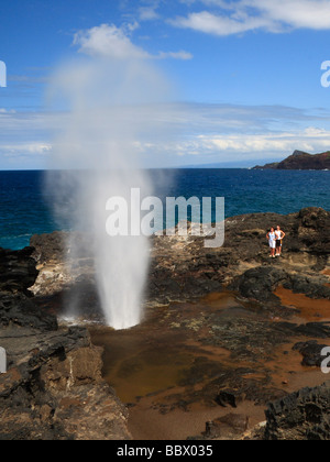 L'eruzione di Nakalele Blowhole sulla North Shore di Maui, con acqua insufflata in aria in alto, con persone che guardano. Foto Stock