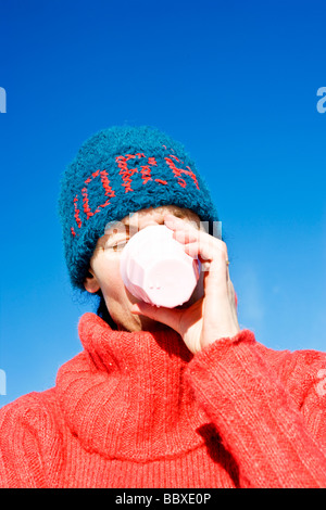 Una donna con un cappello blu di bere da un bicchiere in Svezia. Foto Stock