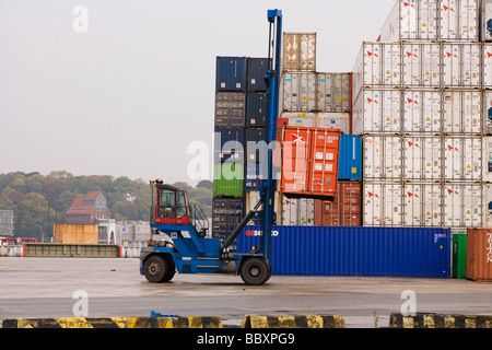 Un contenitore carrello pile e carica i contenitori ISO in un porto. Foto Stock