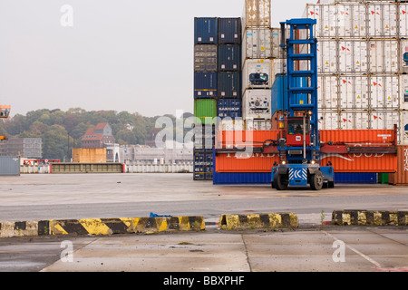 Un contenitore carrello pile e carica i contenitori ISO in un porto. Foto Stock
