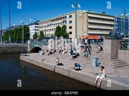 La gente seduta al sole su passi accanto a Sondra Hamn Canal nel centro di Gothenburg in Svezia Foto Stock