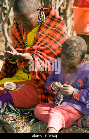 Maasai donna e bambino facendo beadwork - Maji Moto villaggio Masai - vicino a Narok, Kenya Foto Stock