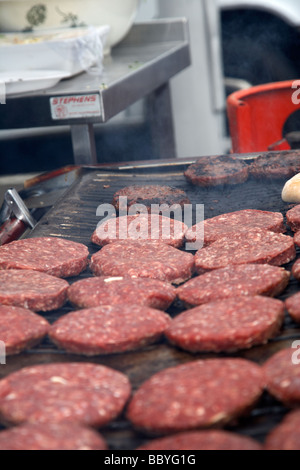 Materie hamburger essendo cotti su una griglia aperta per la vendita a un evento pubblico contea di Down Irlanda del Nord Regno Unito Foto Stock