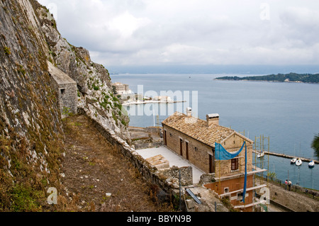 Un edificio ristrutturato a fianco di un porto in cui piccole barche sono ormeggiate, Fortezza Vecchia, citta di Corfu Foto Stock