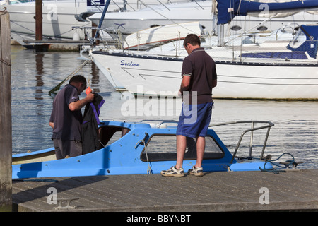 Due uomini a bordo di una piccola imbarcazione a motore moor sul pontile al Jolly Sailor Inn at Burseldon Hampshire REGNO UNITO Foto Stock