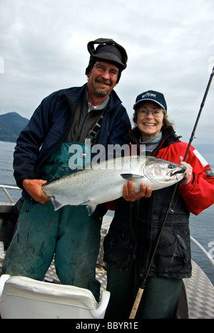 Pescatore femmina indossando resort berretto da baseball con guida di pesca tenendo un appena sbarcati Haida Gwaii Salmone Chinook Foto Stock