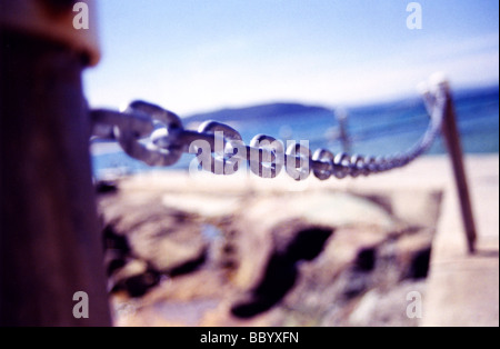 Pali in metallo e la catena lungo la parete del mare Foto Stock