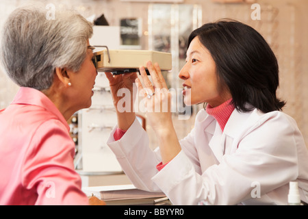 Il coreano ottico dando donna esame oculistico Foto Stock