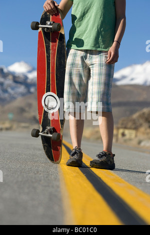 Giovane donna skateboarding in Vescovo, CA con le montagne sullo sfondo. Foto Stock