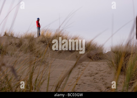 Una giovane donna cammina tra le dune di sabbia, Firenze, Oregon, Stati Uniti. Foto Stock