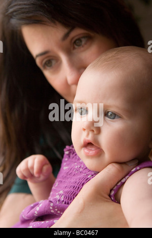 Azienda madre bambina di quattro mesi la ragazza e la bacia la testa, primo piano Foto Stock