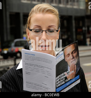 Donna lettura opuscolo informativo su casi di influenza suina Foto Stock