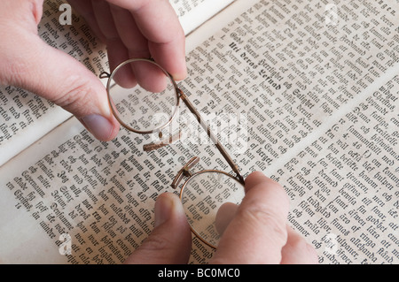Le mani di presa di un paio di pince-nez occhiali sulla bibbia svedese. Foto Stock