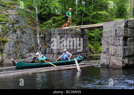 Frinds paddling canoe sotto un ponte di pietra Foto Stock