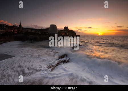 Mare mosso e onde lavaggio in oltre la spiaggia cittadina al tramonto a Ilfracombe North Devon Regno Unito Foto Stock