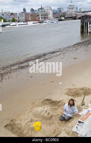 Un artista che lavora su una scultura di sabbia su una spiaggia sulla riva sud del fiume Tamigi London REGNO UNITO Foto Stock