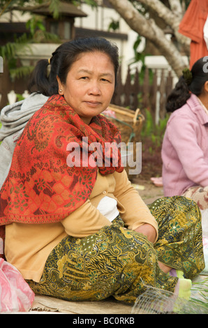 Un ritratto di una donna Lao seduta gambe incrociate al suo livello di pavimentazione in stallo in Luang Prabang quotidiana del mercato alimentare Foto Stock