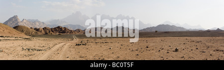 Panorama attraverso il deserto piano distante gamme della montagna con auto le vie che portano a shot, il Deserto Orientale dell Egitto, Africa Foto Stock