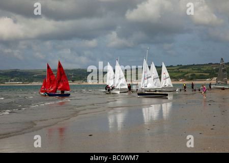 Beached White Barche a vela, yacht laser in mare, dingies e rimorchi a Marazion, vicino al Monte di San Michele, Penzance in Cornovaglia. Foto Stock