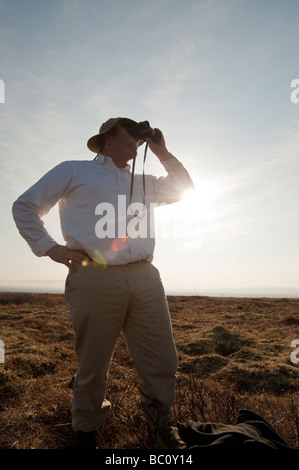 Un bird watcher guarda attraverso il suo binocolo Foto Stock