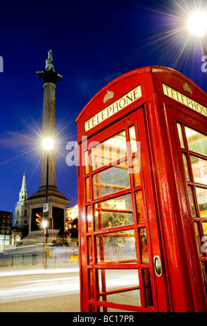 British telefono pubblico box a Trafalgar Square. In fondo è di Nelson's colonna. Esposizione a lungo con il traffico motion blur. Foto Stock