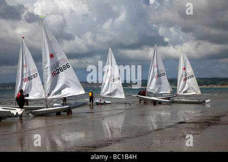 Beached White Barche a vela, yacht laser in mare, dingies e rimorchi a Marazion, vicino al Monte di San Michele, Penzance in Cornovaglia. Foto Stock