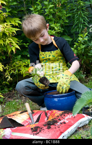 Giovane maschio giardiniere Riempimento vaso da giardino con il compost Foto Stock