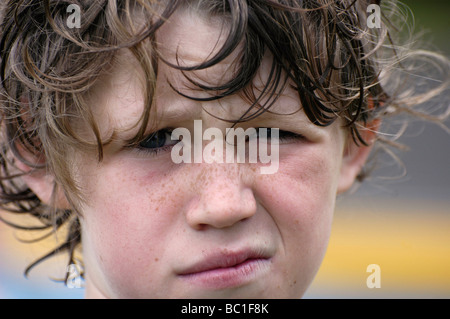 A dieci anni ragazzo con disordinati capelli cercando dubbia Foto Stock