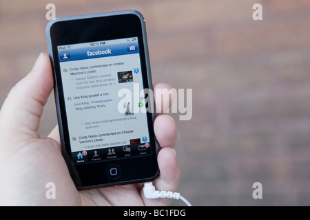 Un uomo utilizza l'applicazione Facebook su un Ipod Touch di Apple. Foto Stock