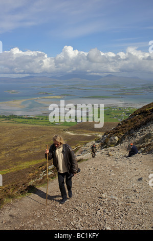 Una donna con un bastone da passeggio climbing Croagh Patrick nella contea di Mayo in Irlanda Foto Stock