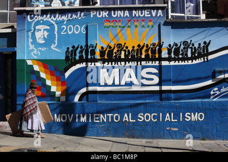 Aymara anziana signora o cholita passando Movimiento al Socialismo partito politico murale sulla parete, La Paz , Bolivia Foto Stock