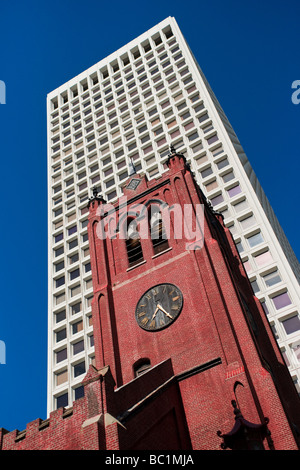 Una vecchia chiesa di mattoni insieme contro un ufficio moderno edificio. Foto Stock