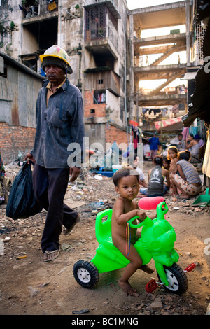 Costruzione di sesso maschile il lavoratore e il bambino che gioca con la sua bunny carrello in 'Dey Krahorm' delle baraccopoli zona nel centro di Phnom Penh Cambogia Foto Stock