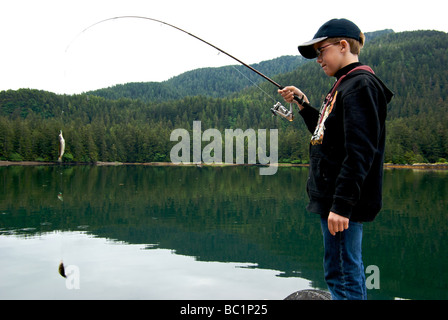 Ragazzo con un paio di piccoli shiner pesce persico dibattere in motion blur catturati su una maschera di aringhe in Haida Gwaii Foto Stock