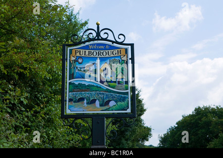 Legno e metallo Pulborough Village segno con ponte Stopham, Main Street e la Chiesa Parrocchiale di Santa Maria. West Sussex, in Inghilterra, Regno Unito Foto Stock