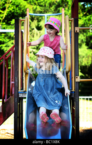 2 2 3 anno di età i bimbi più ragazze migliori amici giocando sulla slitta nel parco locale sorridente ridere outdoor activity giocare estate REGNO UNITO Foto Stock