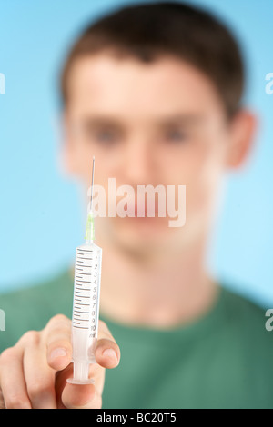 Ragazzo adolescente tenendo la siringa Foto Stock