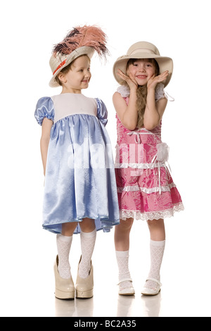 Due bambine in cappelli con piume e pelliccia e la mamma s scarpe isolato su bianco Foto Stock