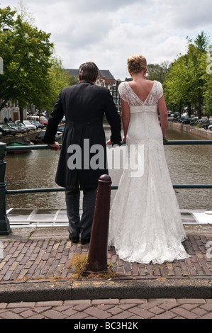 Sposa e lo Sposo stare in piedi su un ponte sul canale Prinsengracht in Amsterdam Foto Stock