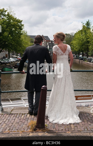 Sposa e lo Sposo stare in piedi su un ponte sul canale Prinsengracht in Amsterdam Foto Stock