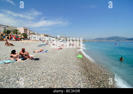 La gente a prendere il sole e godere la famosa spiaggia di ciottoli di Nizza sulla costa Azzurra, Francia meridionale. Foto Stock