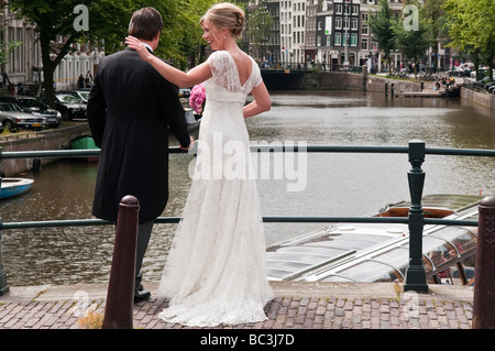 Sposa e lo Sposo stare in piedi su un ponte sul canale Prinsengracht in Amsterdam Foto Stock