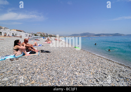 La gente a prendere il sole e godere la famosa spiaggia di ciottoli di Nizza sulla costa Azzurra, Francia meridionale. Foto Stock