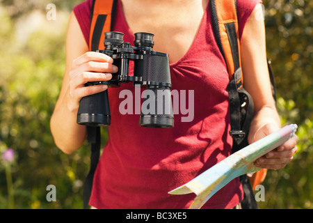 Vista ritagliata della femmina di bird watcher tenendo il binocolo e mappa Foto Stock